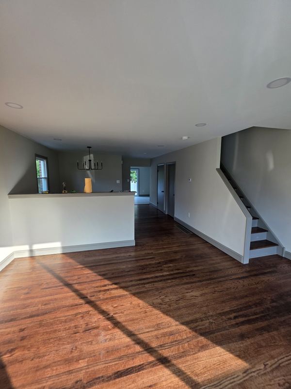 Open living area with fresh interior paint, new baseboard trim and painted stair skirt