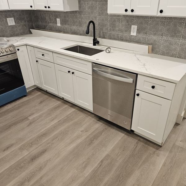 Renovated kitchen with white shaker cabinets, quartz counters and tile backsplash