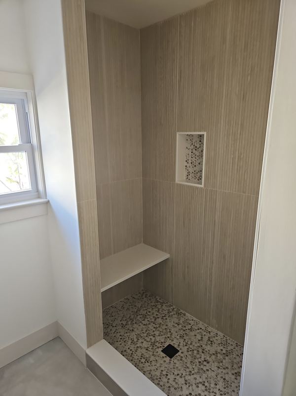 Custom tiled walk-in shower with niche and built-in bench